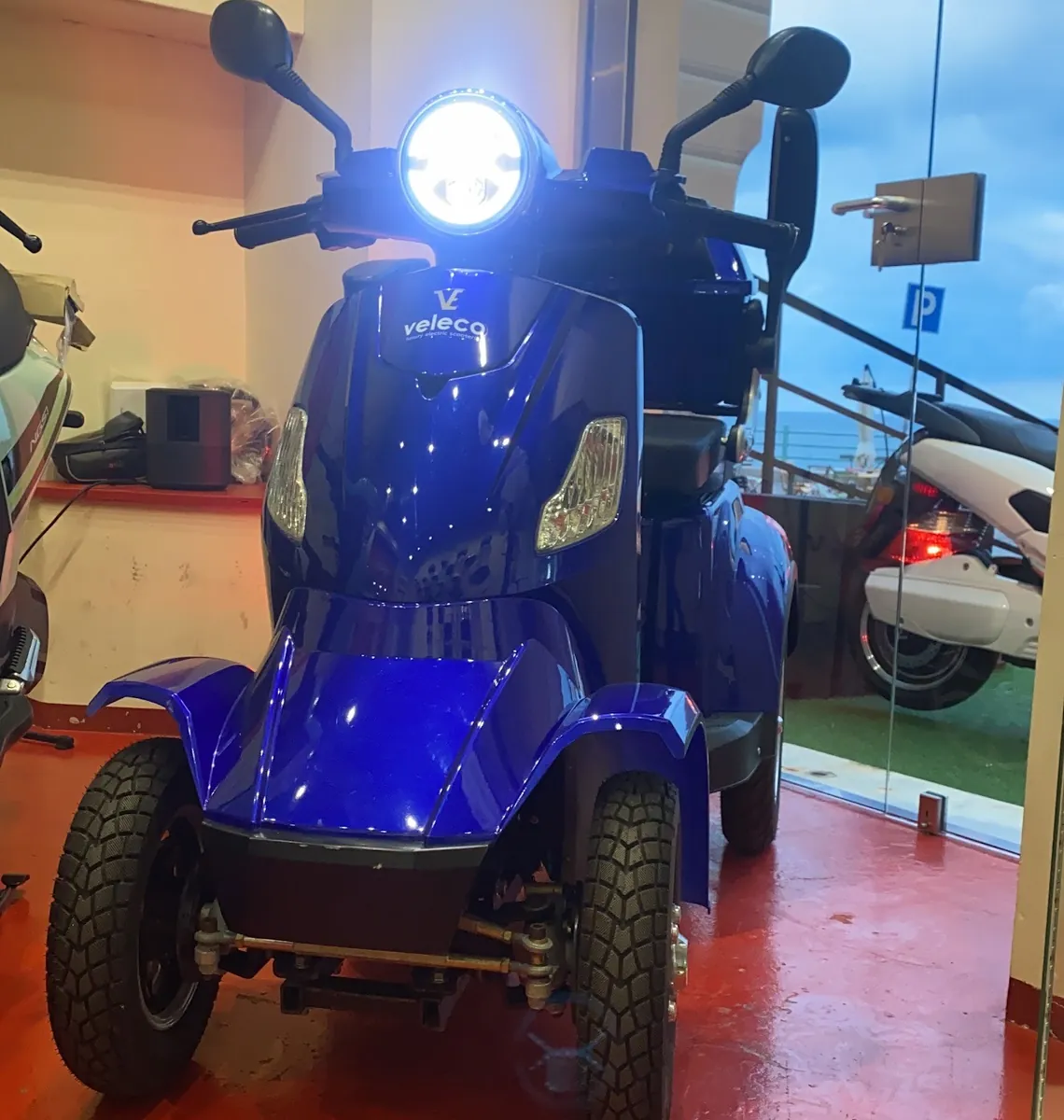 Veleco Faster blu a quattro ruote all'interno dello showroom di Genova